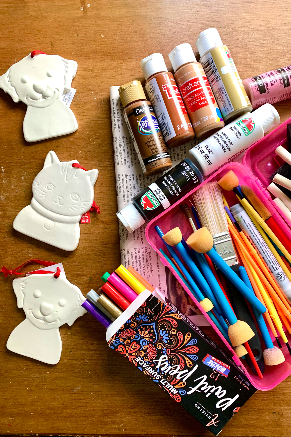 Unpainted ceramic cat and dog ornaments, assorted paint and brushes.