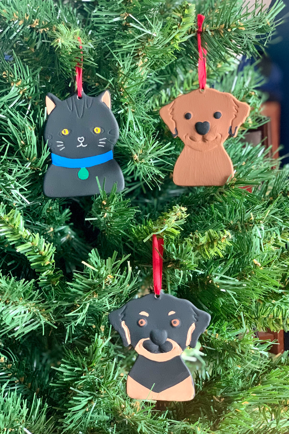 Painted pet ornaments of a black cat, brown dog, and black/brown dog.