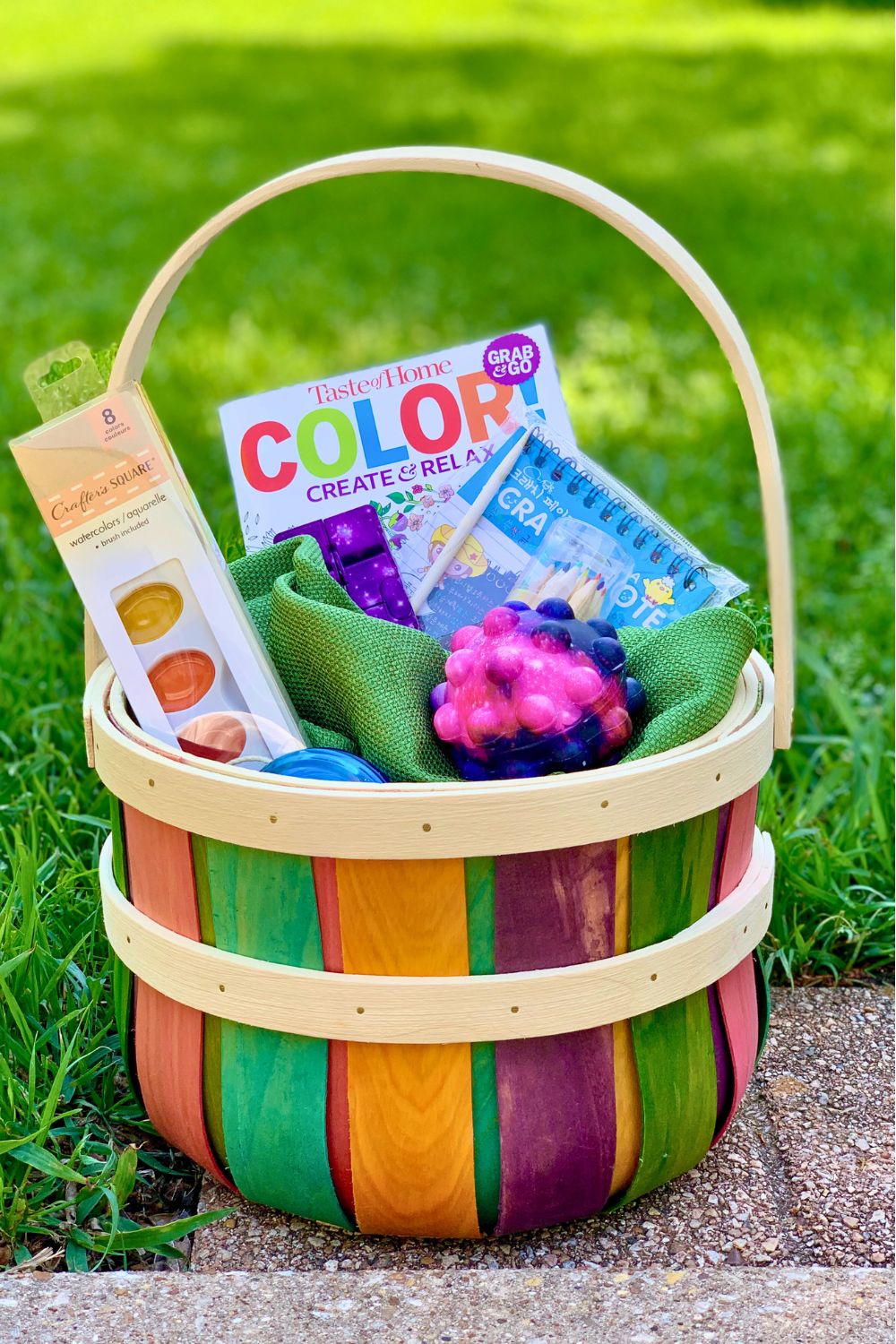 An Easter basket filled with a coloring book, scratch art kit, fidget toys, watercolor paints, and a yo-yo.