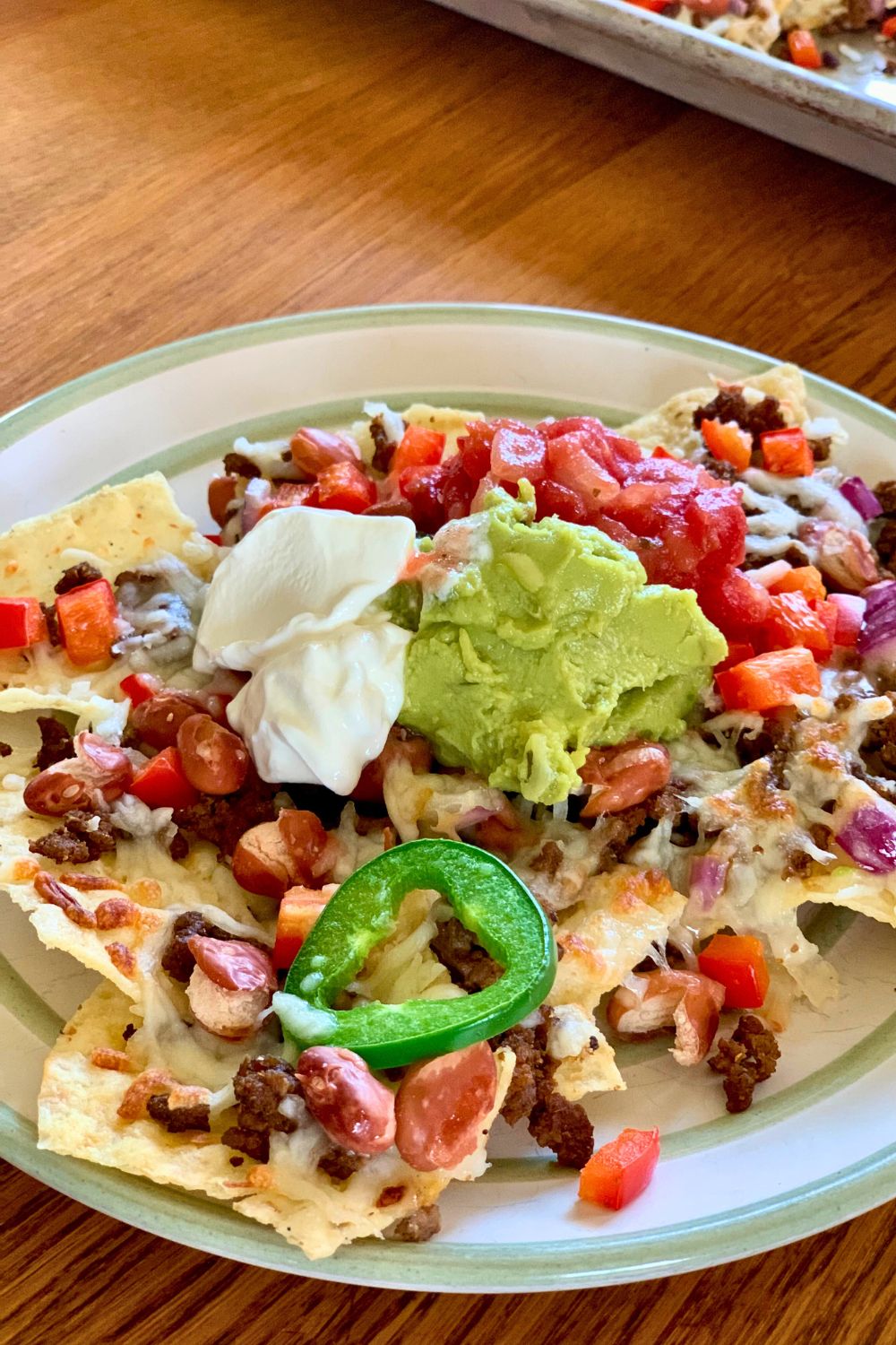 A plate of nachos with dollops of guacamole, sour cream, and salsa in the middle.