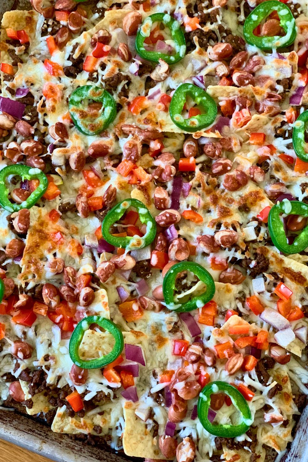 Closeup of nachos showing browned melted cheese covering the other toppings.