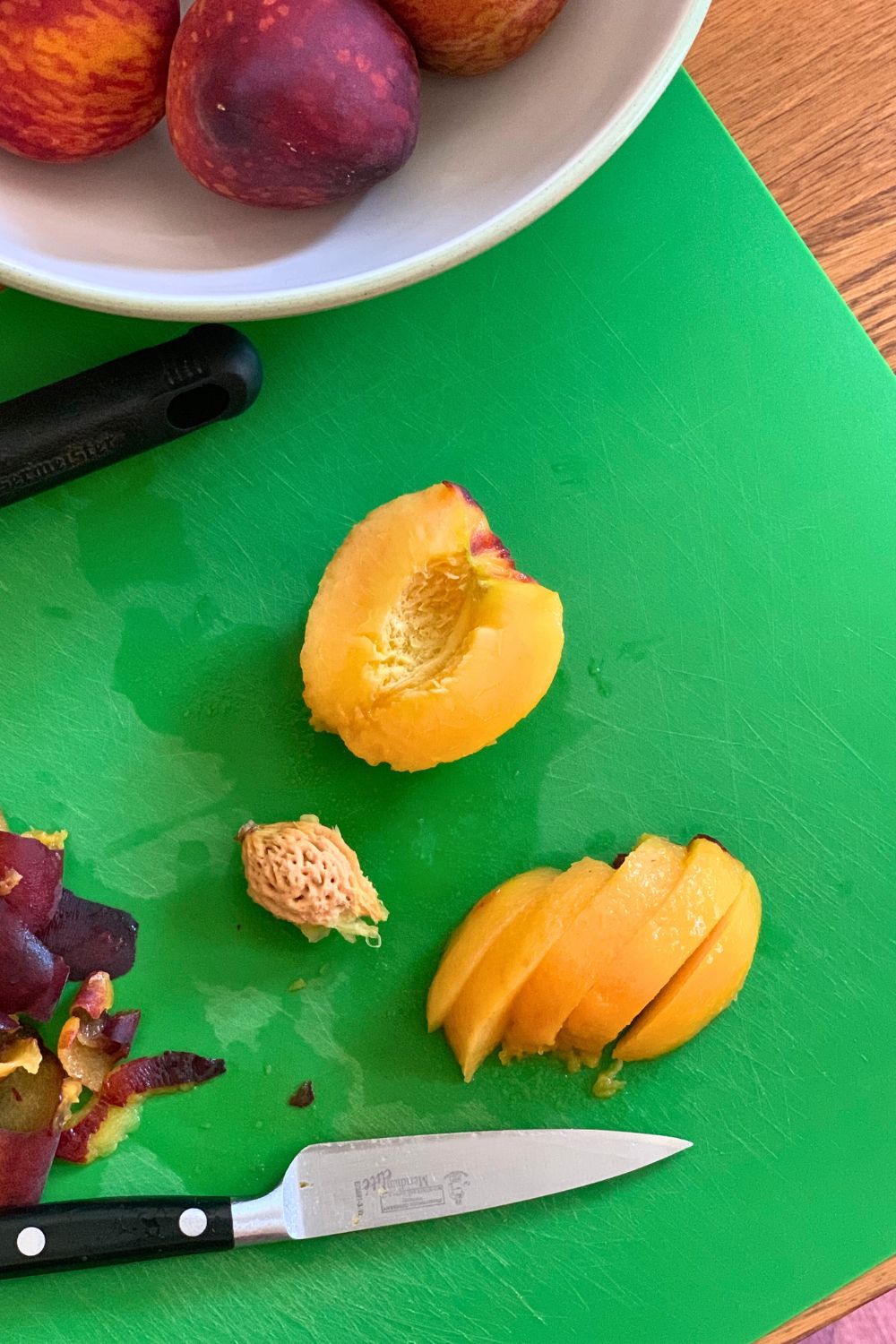 A half peach beside slices of peach.