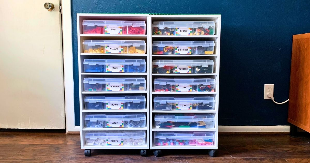 White rolling shelves with 14 scrapbook paper boxes labeled for lego storage.