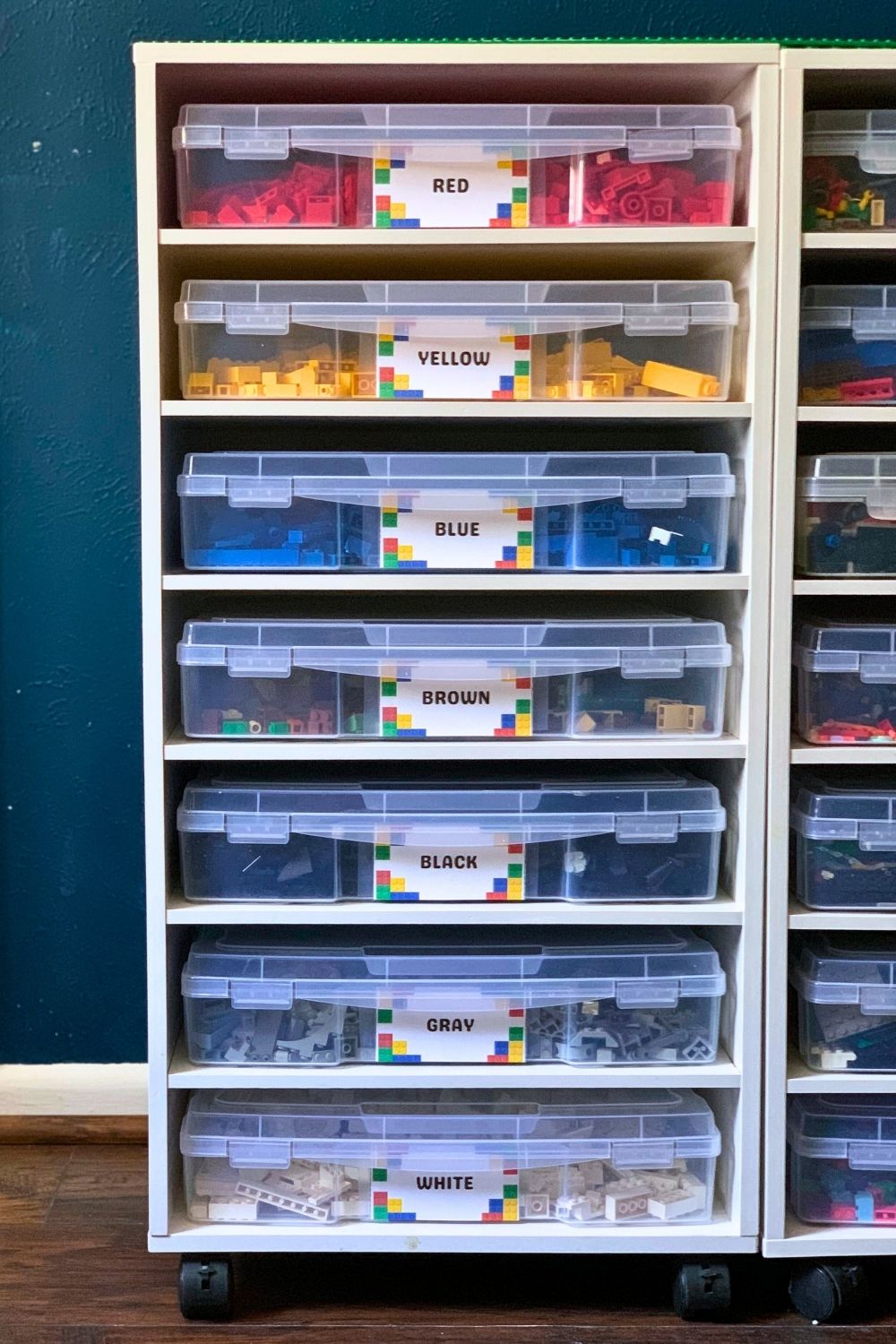 A white rolling craft shelf filled with scrapbook paper drawers to hold lego pieces sorted by color.