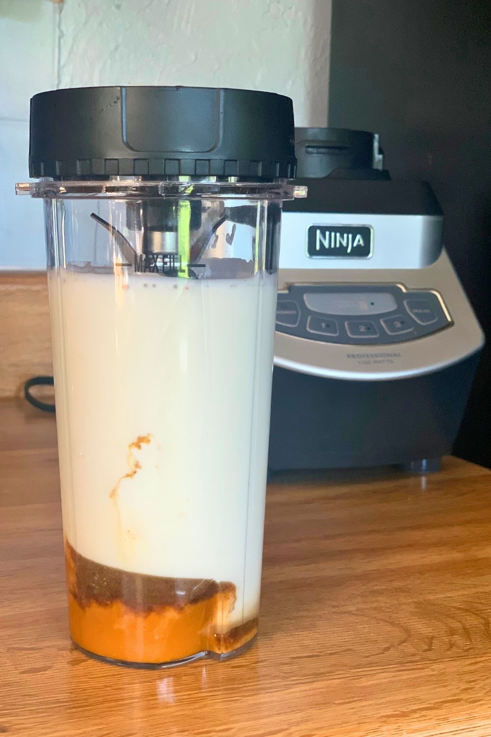A blender cup filled with pumpkin puree, brown sugar, cinnamon, yogurt, and milk.