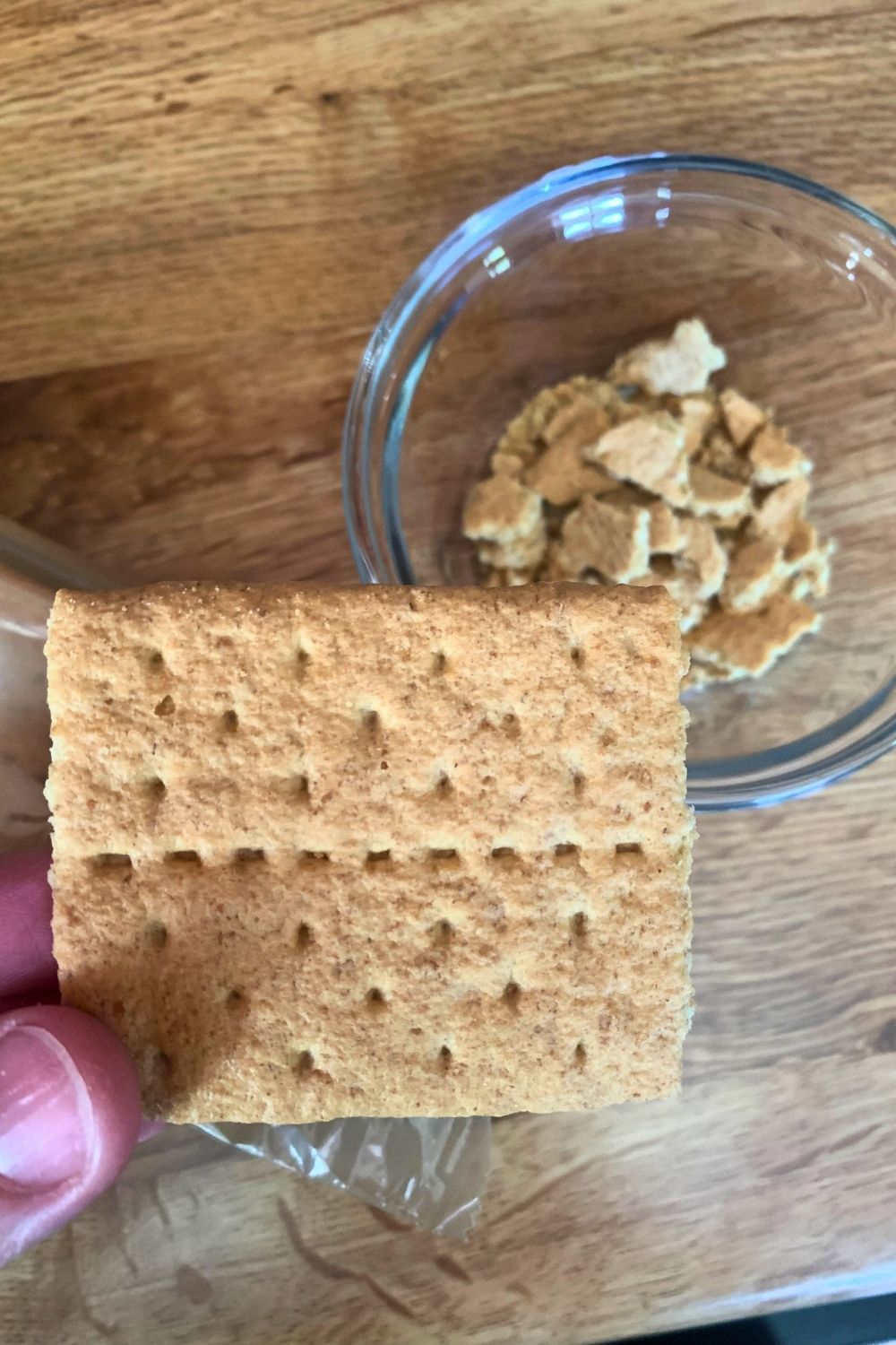 Half a graham cracker beside a bowl of cracker crumbles.