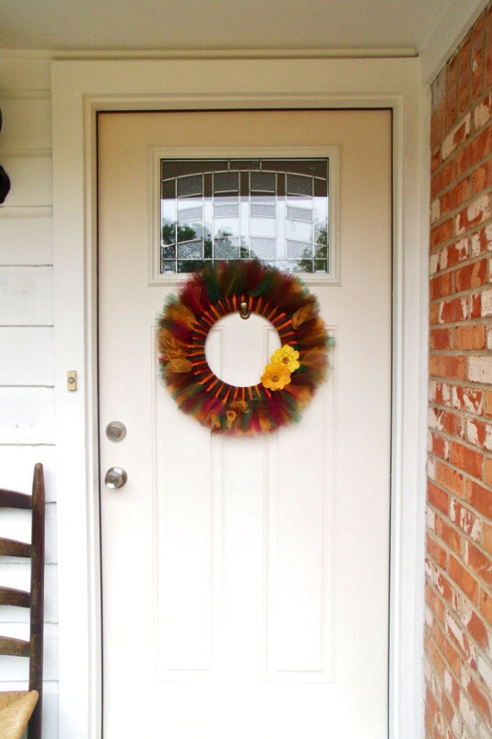 A jewel-toned fall tulle wreath hanging on a white door.