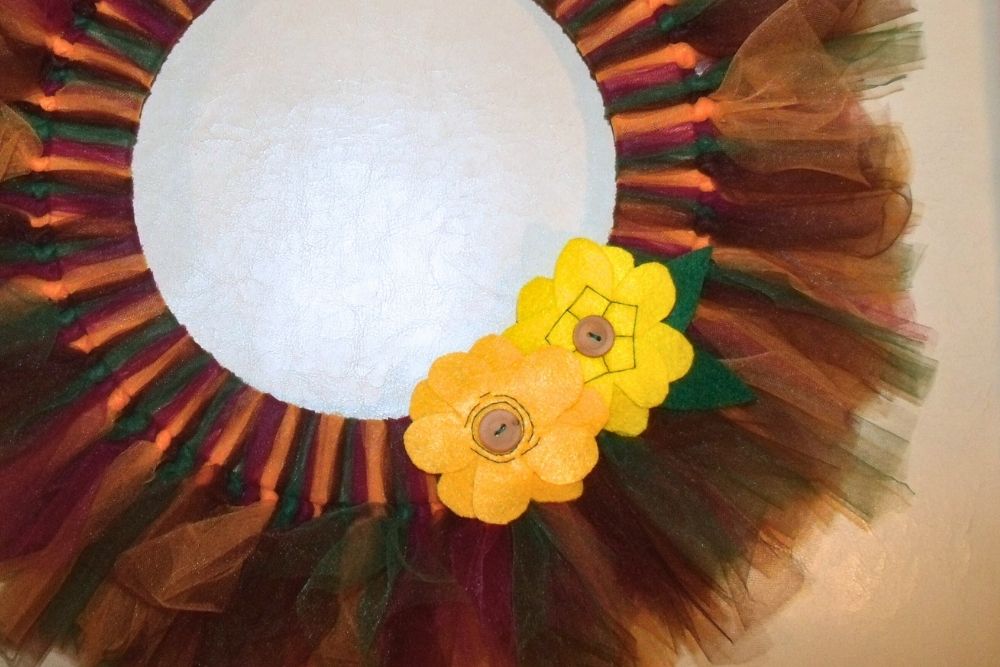 Closeup of handmade yellow and orange felt flowers with wood button centers.