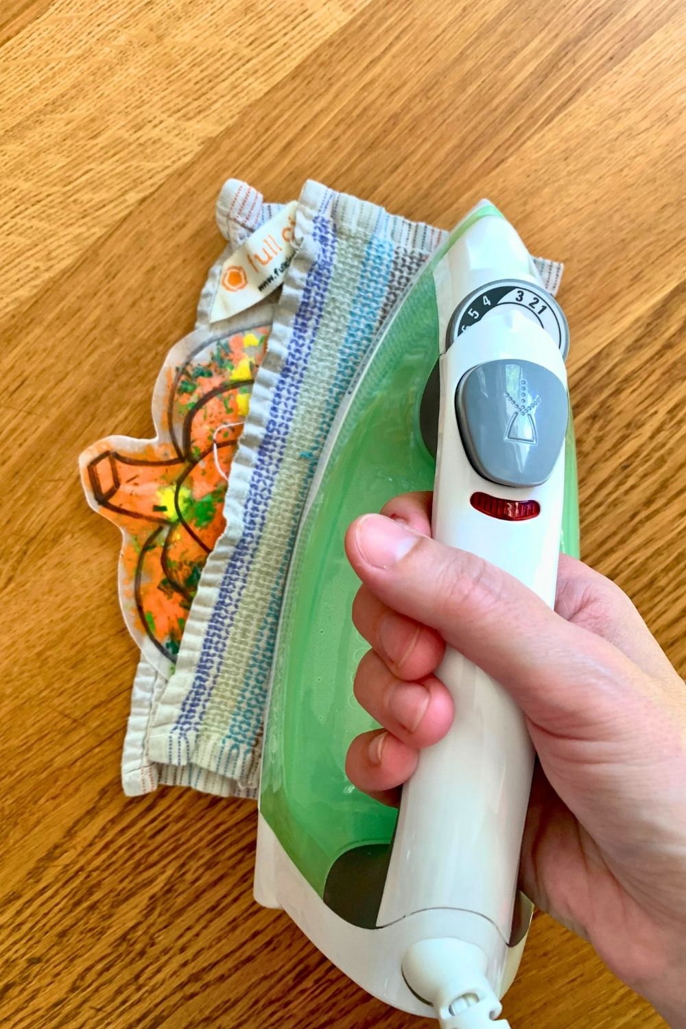 Ironing the edges of the melted crayon pumpkin between towels.