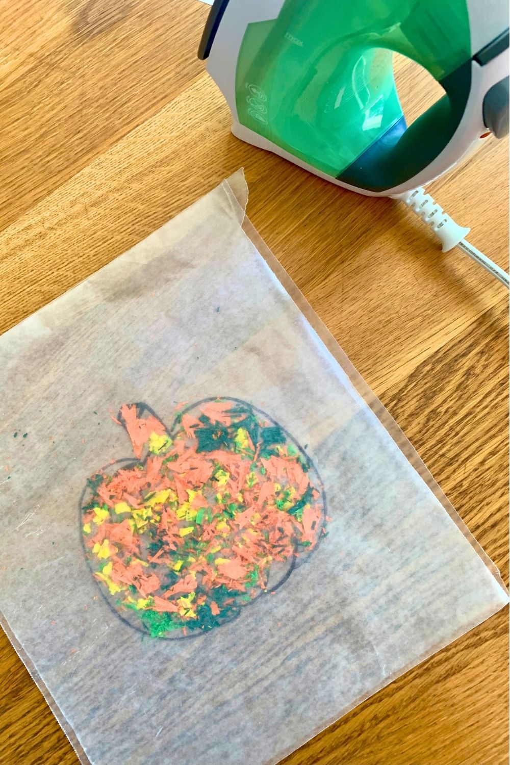 Layering wax paper over the crayon shavings on the pumpkin outline.