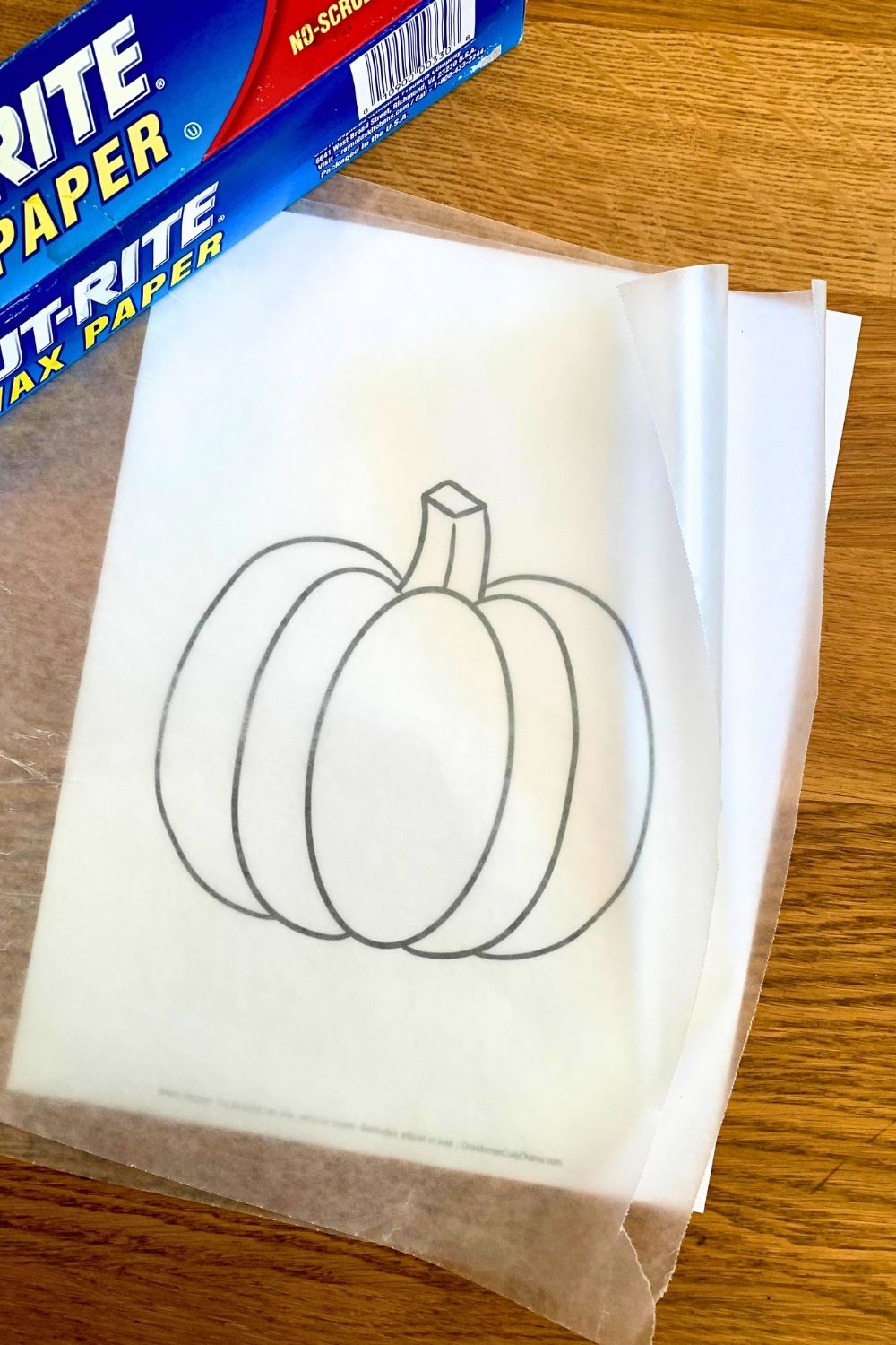 Two pieces of wax paper layered over a drawing of a pumpkin.