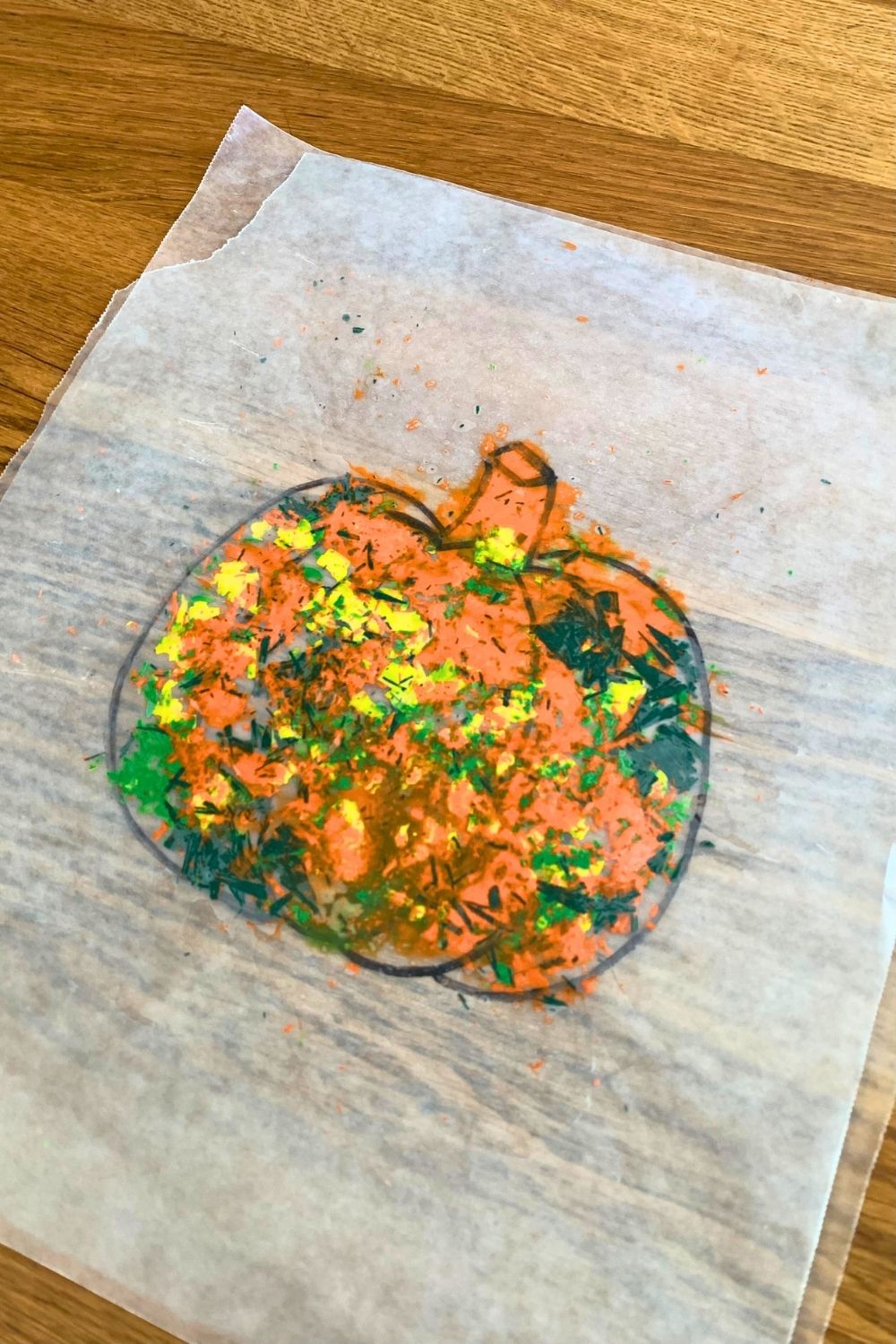 Melted crayon shavings between the wax paper in a pumpkin shape.