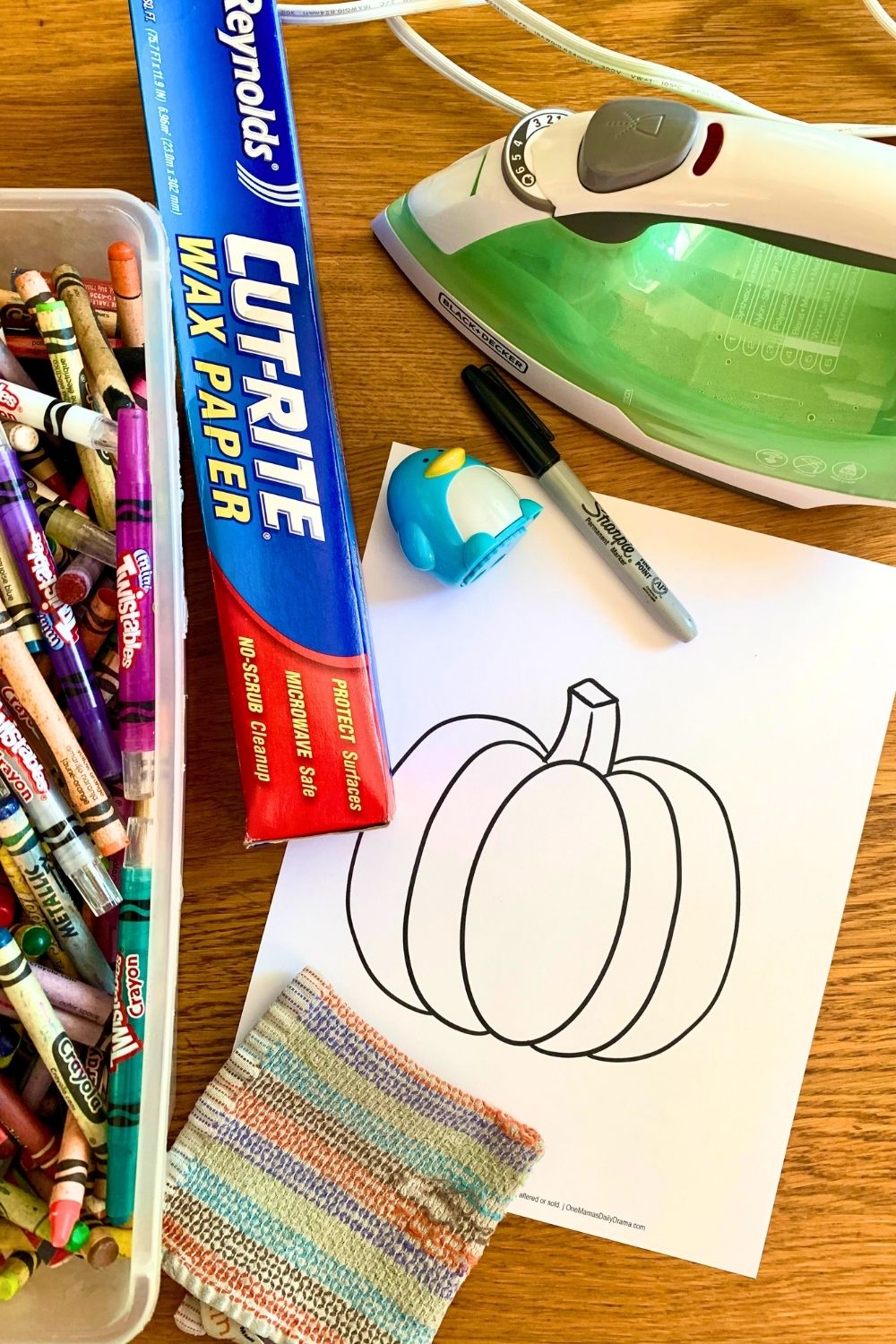 A box of crayons, roll of wax paper, iron, permanent marker, pencil sharpener, and pumpkin template.