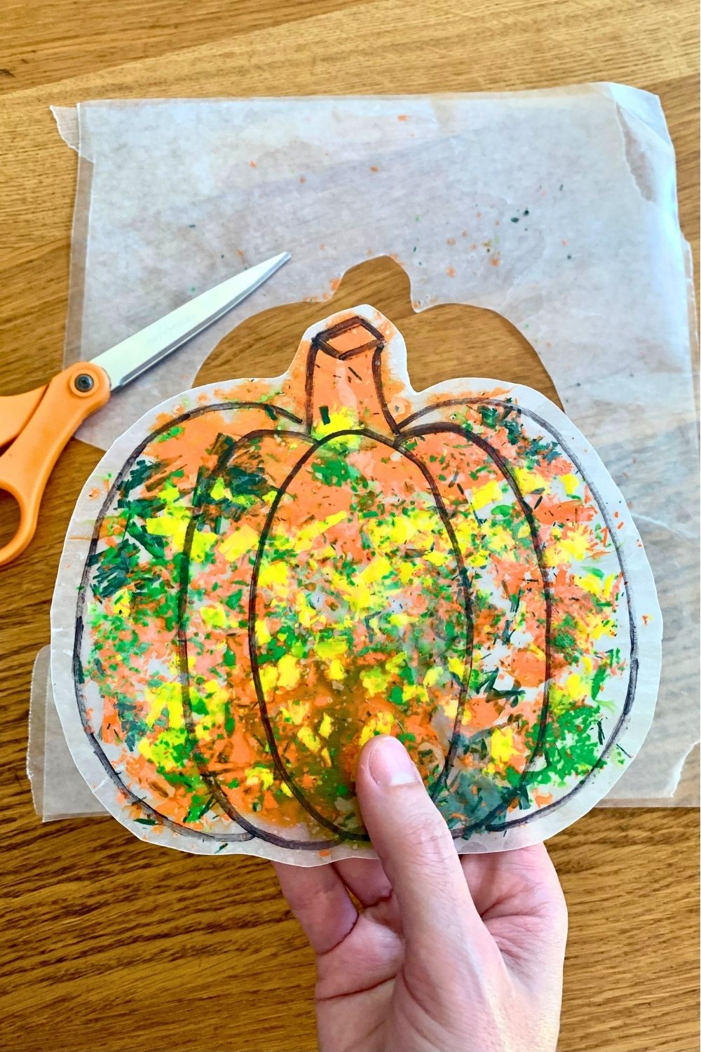Trimming the edge of the wax paper around the melted crayon pumpkin.
