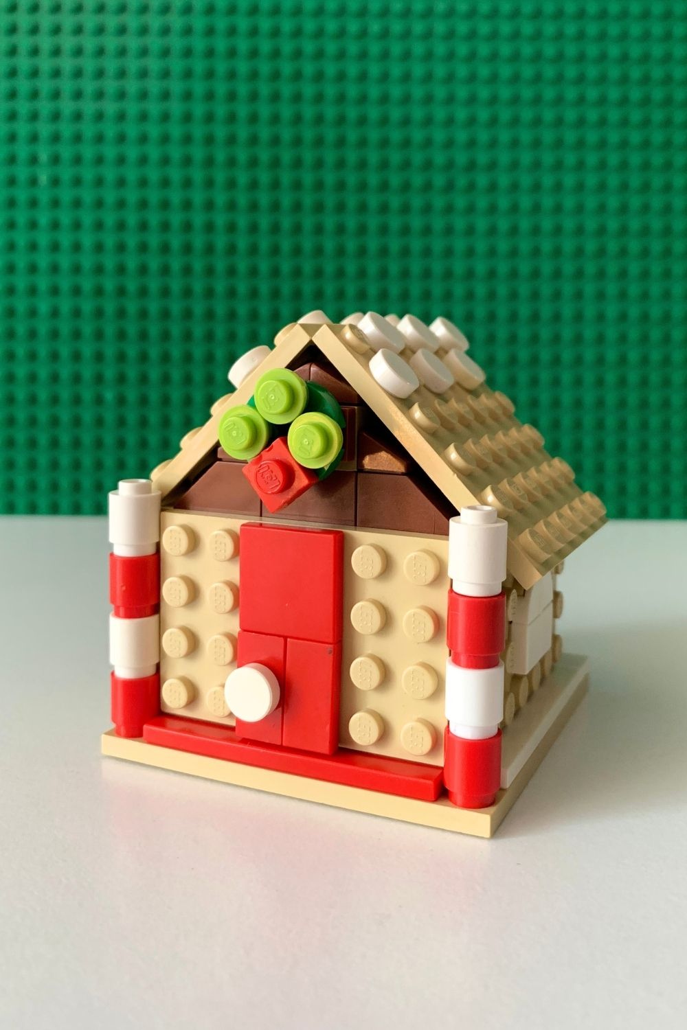 Red and white barrel pieces stacked to resemble candy canes at the corners of the house.