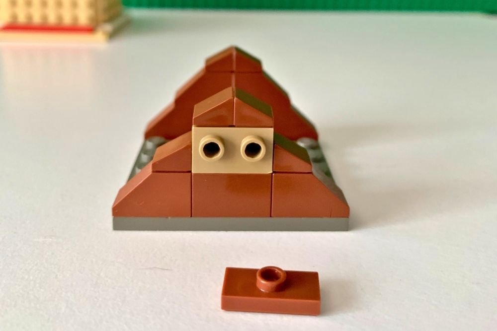 A baseplate with brown slopes stacked to make a triangle on either end. The center piece has 2 side studs.