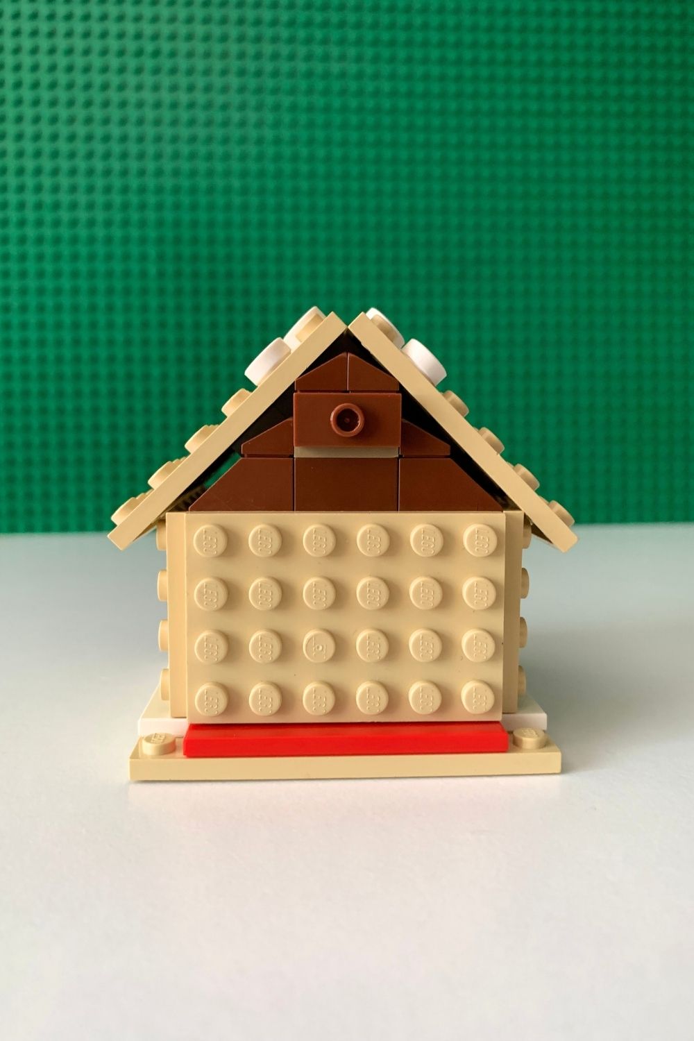 A plain LEGO gingerbread house with tan baseplates for the base, 4 walls, and 2 roof pieces.