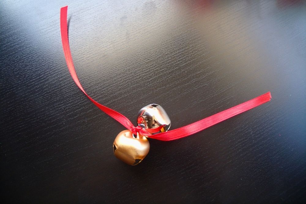 A pair of jingle bells tied to a red ribbon.