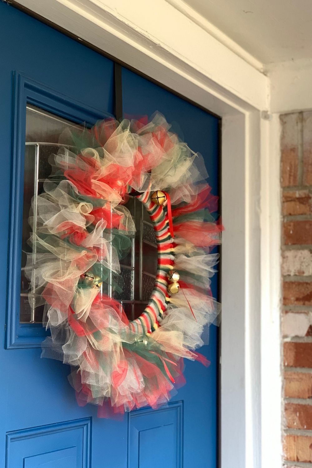 Red, gold, green, and silver tulle Christmas wreath with jingle bells.