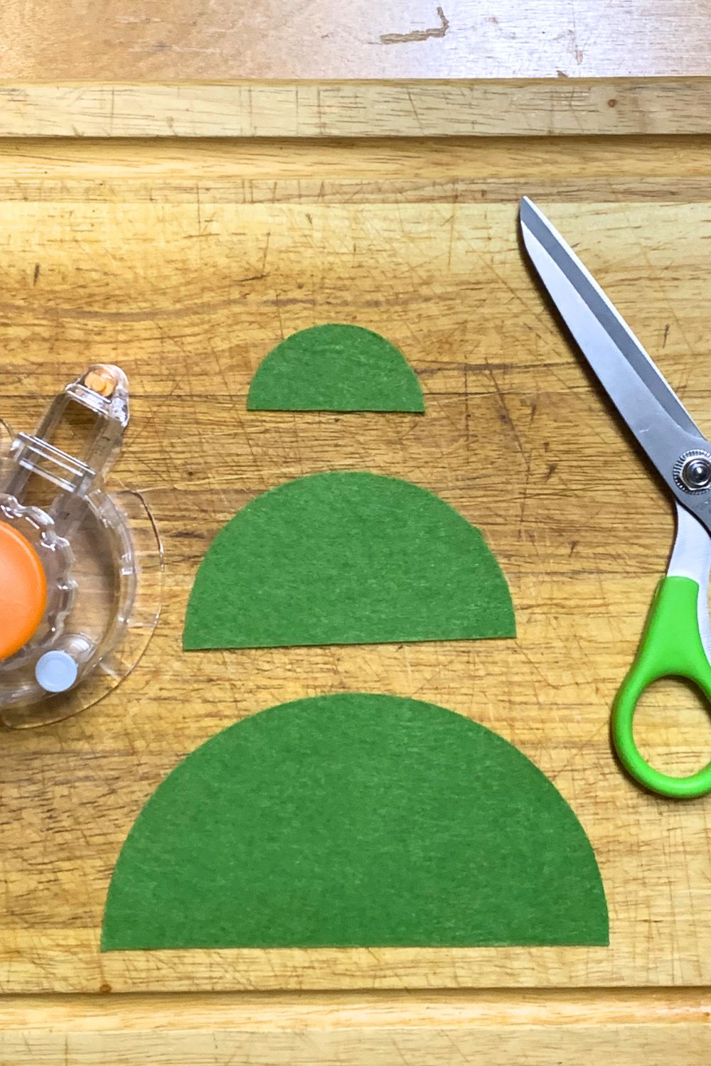 Three green felt half-circles in different sizes on a cutting board.