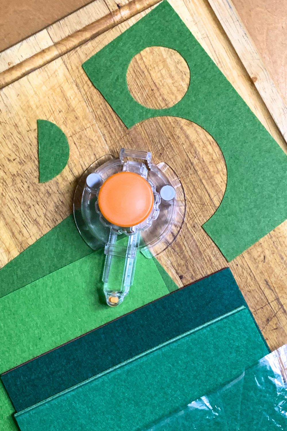 Green craft felt stacked beside a circle cutting tool.