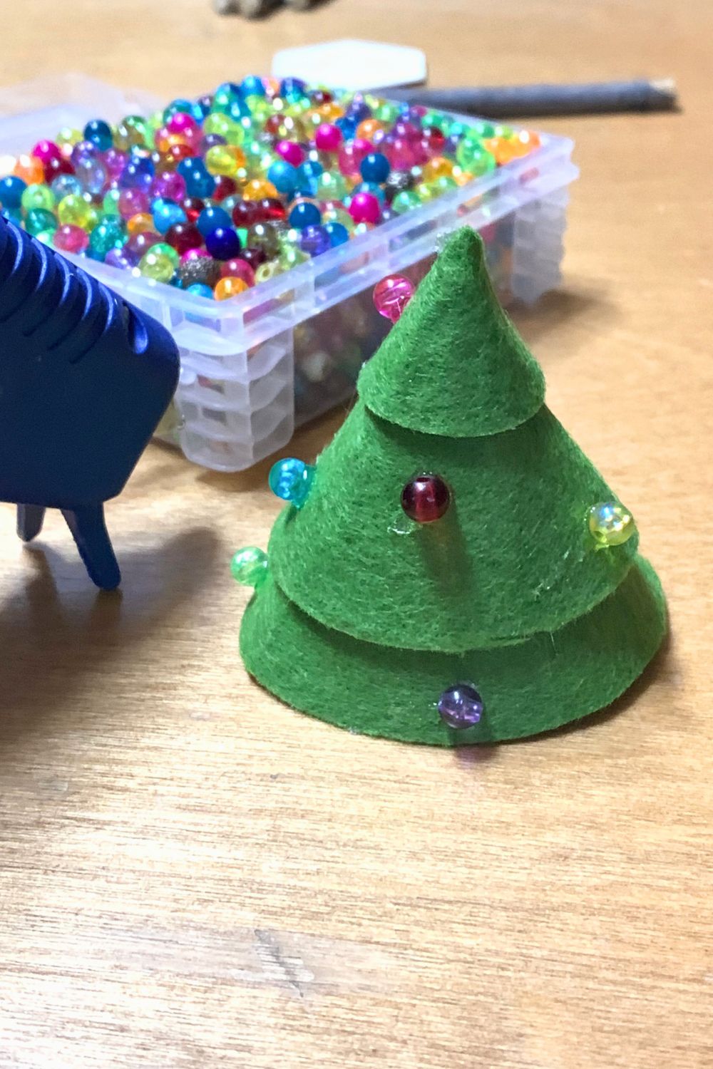 Hot gluing colorful beads onto the felt cone.