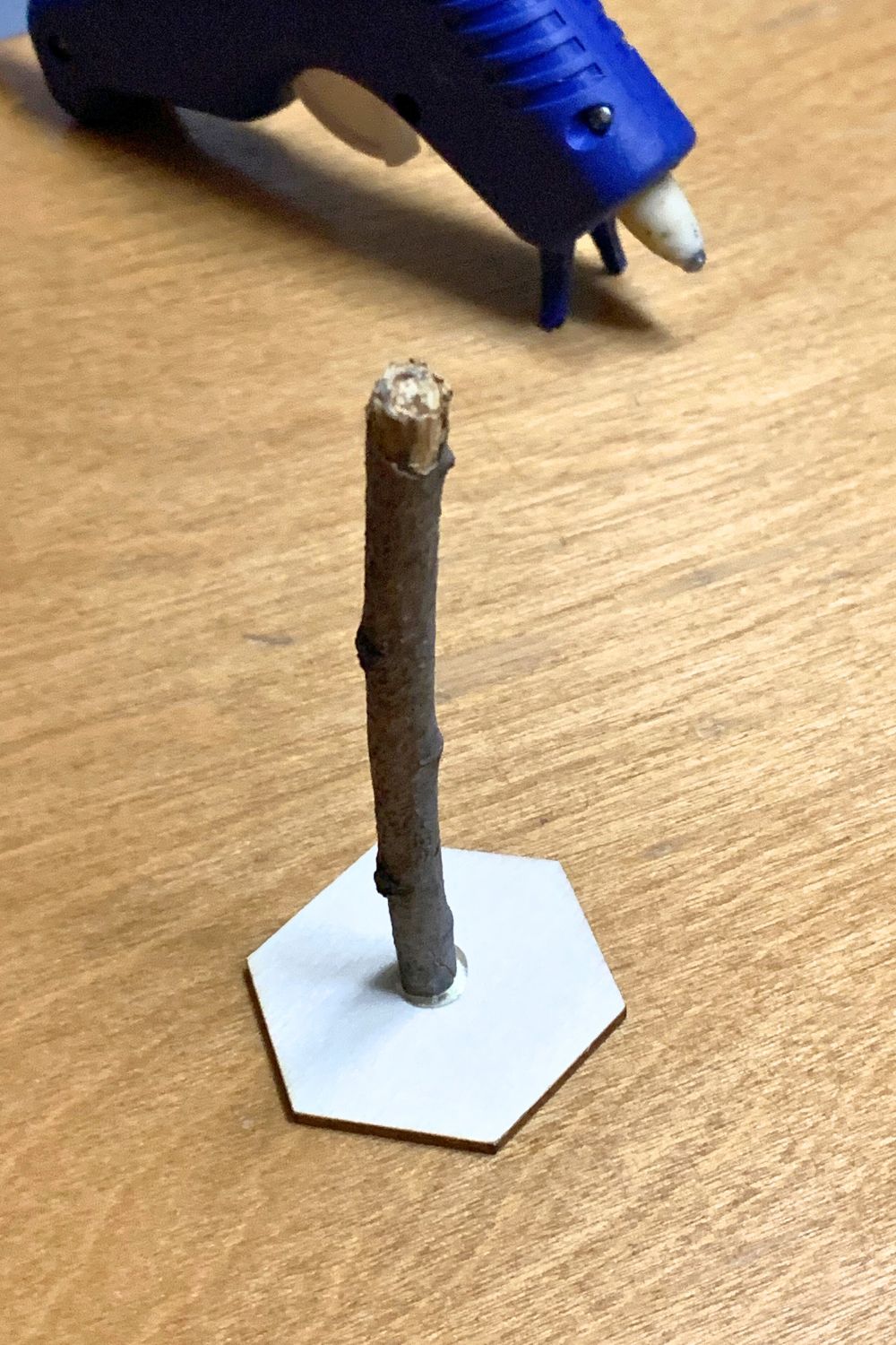 A small stick glued to an unfinished wood hexagon shape.