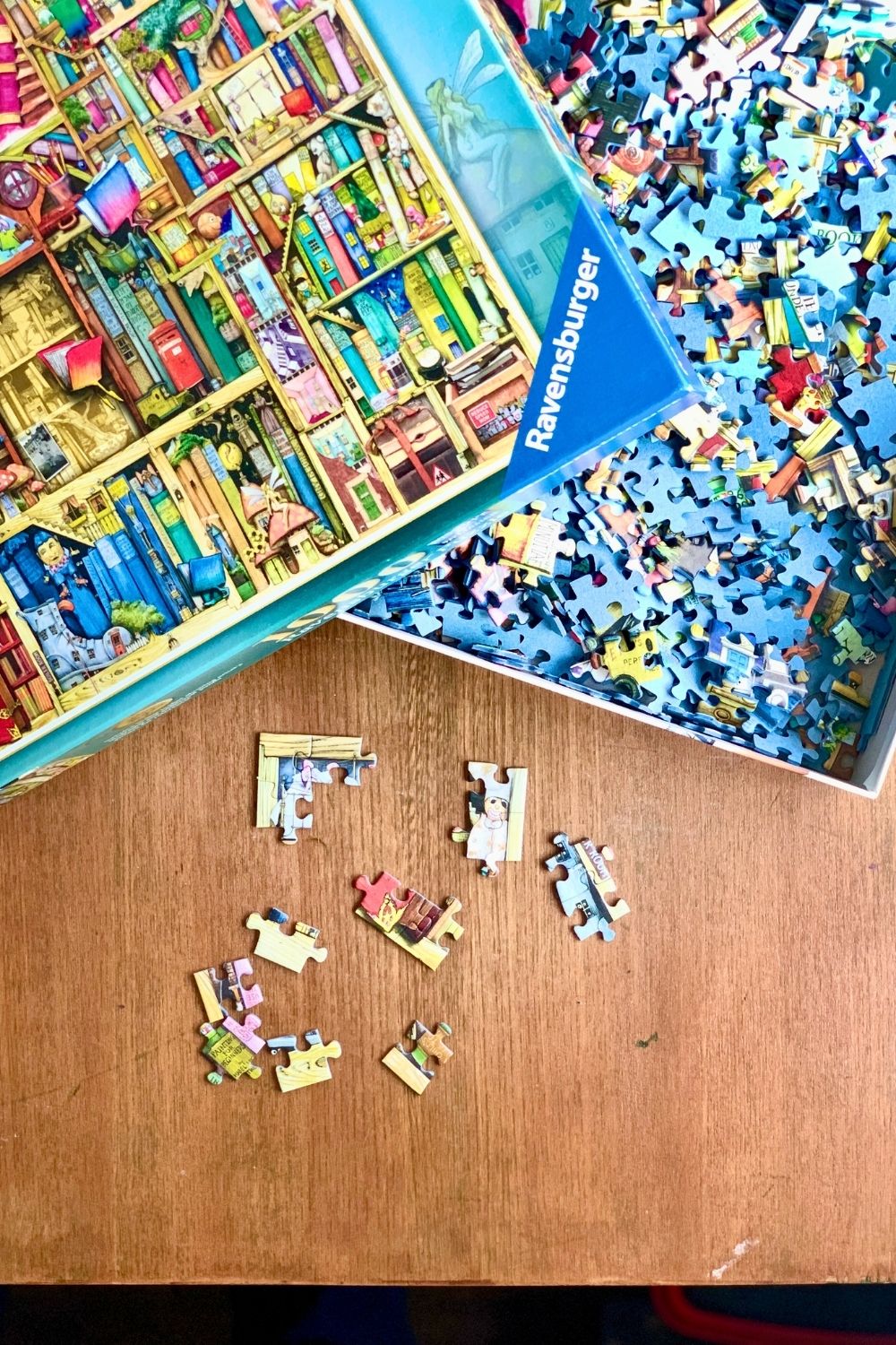 A puzzle box open with a few pieces removed and stuck together on a table.