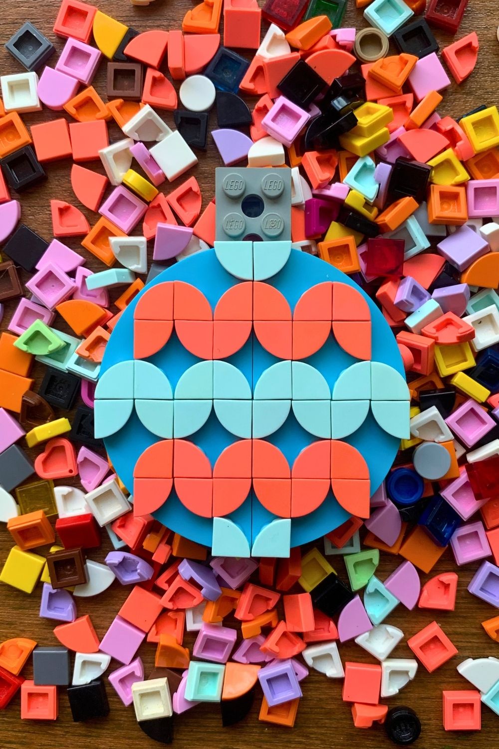 A blue LEGO circle decorated with pink and blue wedge dots in a squiggly pattern.