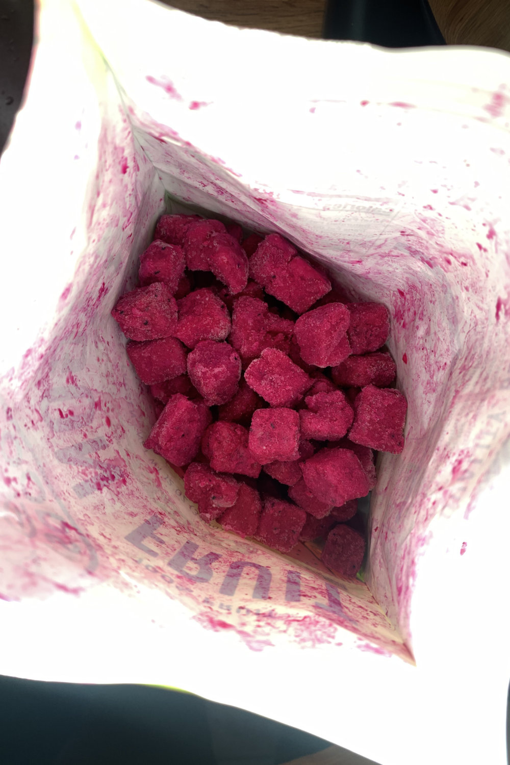 Closeup inside a bag of frozen pink dragon fruit cut into bite-sized pieces.