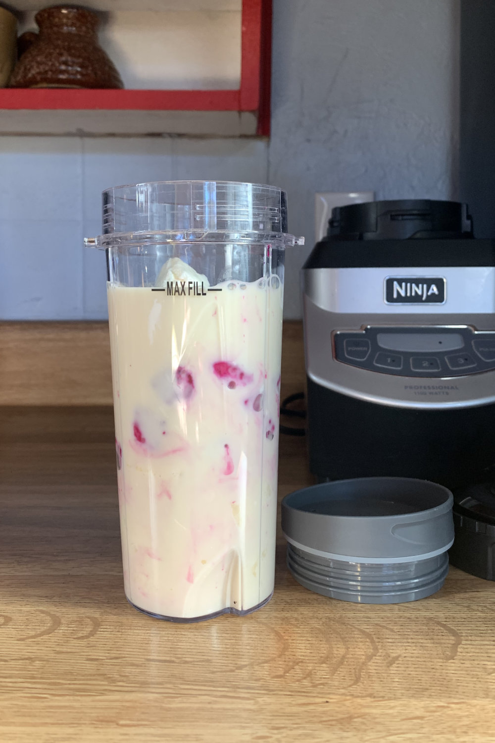 A plastic cup with milk poured over the other ingredients.