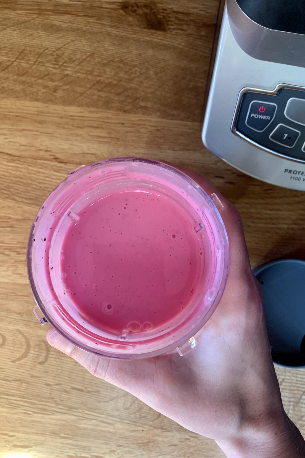 Overhead view of a bright pink drink in a clear plastic tumbler.