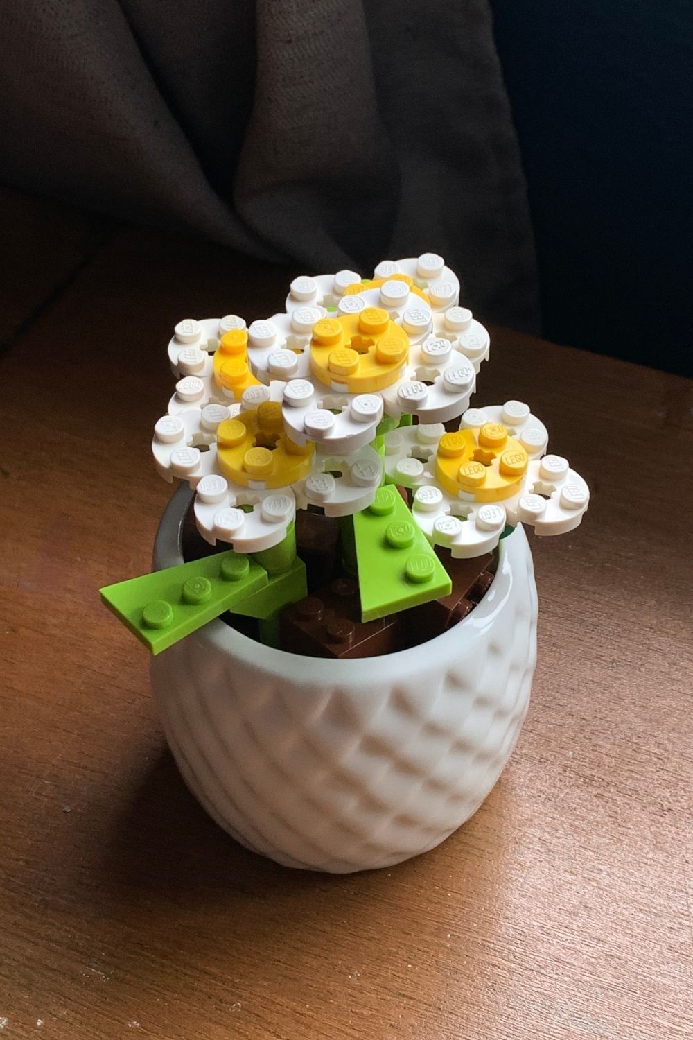 Yellow and white LEGO daisy flowers clustered in a small ceramic pot.