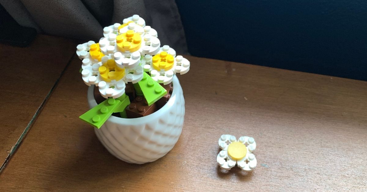 Yellow and white LEGO daisy flowers clustered in a small ceramic pot.