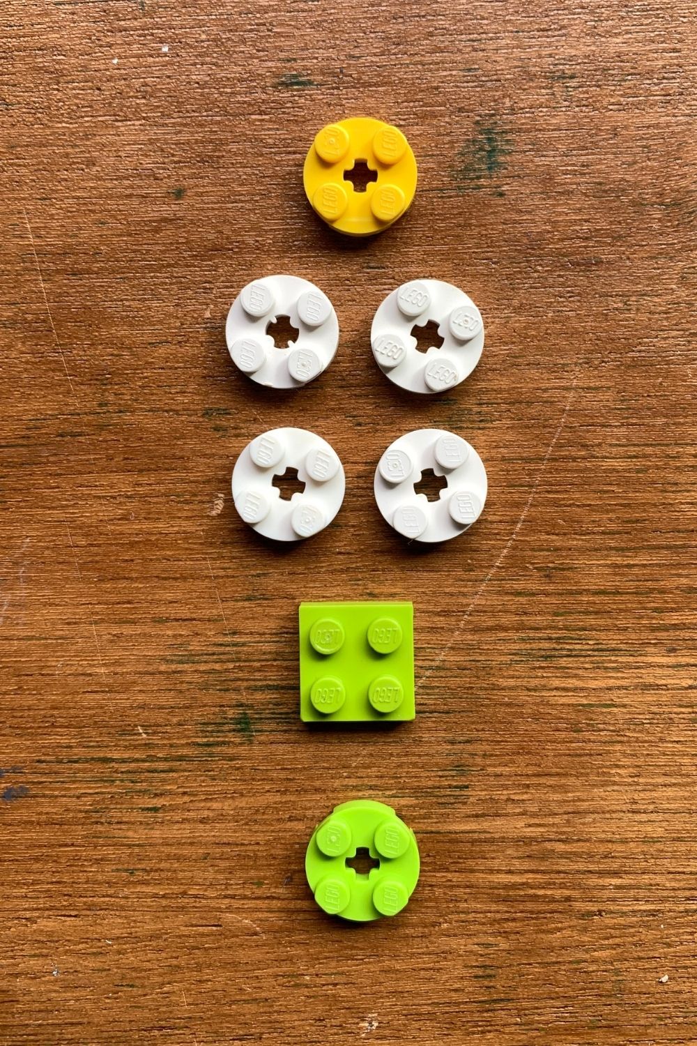 LEGO pieces: a yellow circle, 4 white circles, a green square, and a green circle.