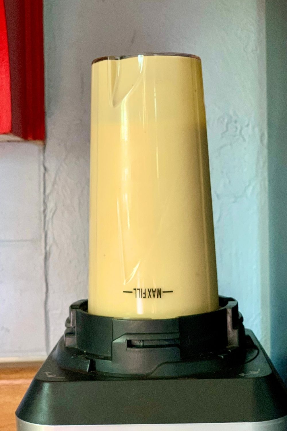 A blender cup affixed to the motor and filled with a golden yellow mixture.