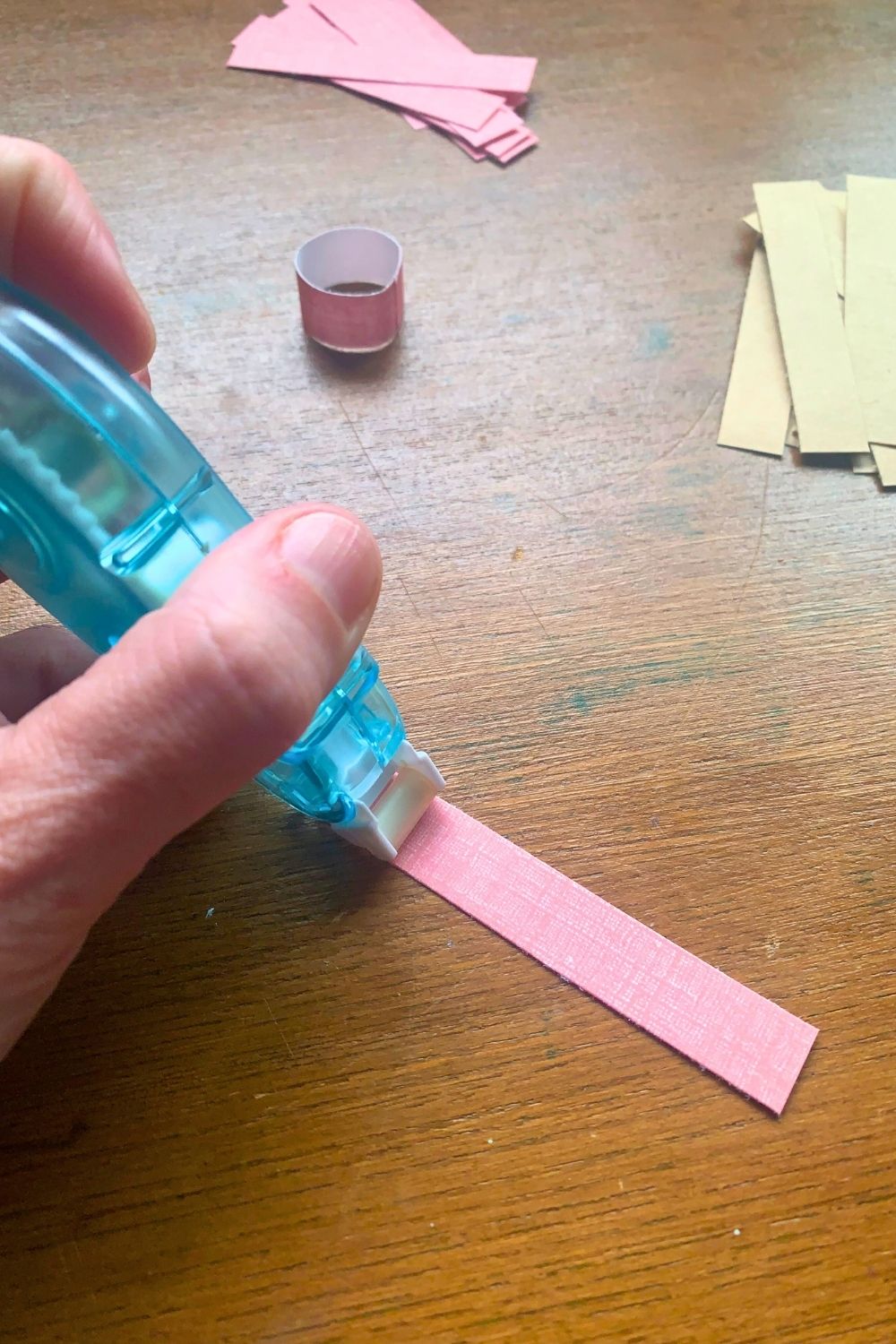 Adding glue to the end of a paper strip.