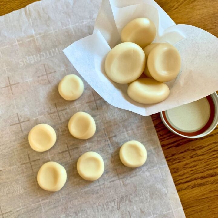 Small pieces of homemade lemon drop candy on parchment paper and in a lined jar.
