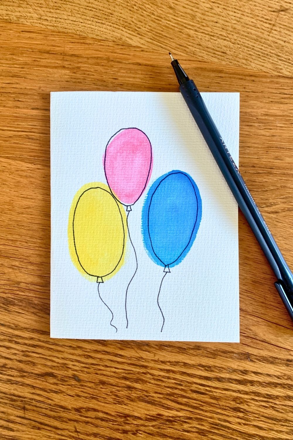 Outlining painted circles in black pen to look like balloons.