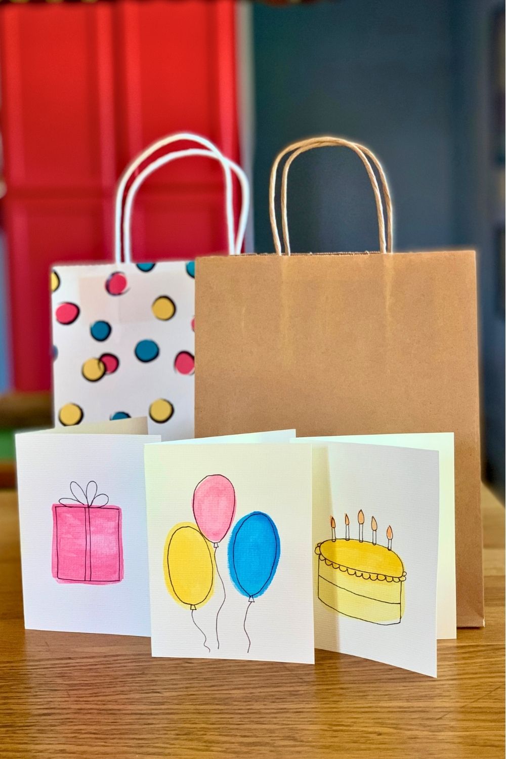 Three birthday cards with watercolor illustrations of a gift, balloons, and a cake.