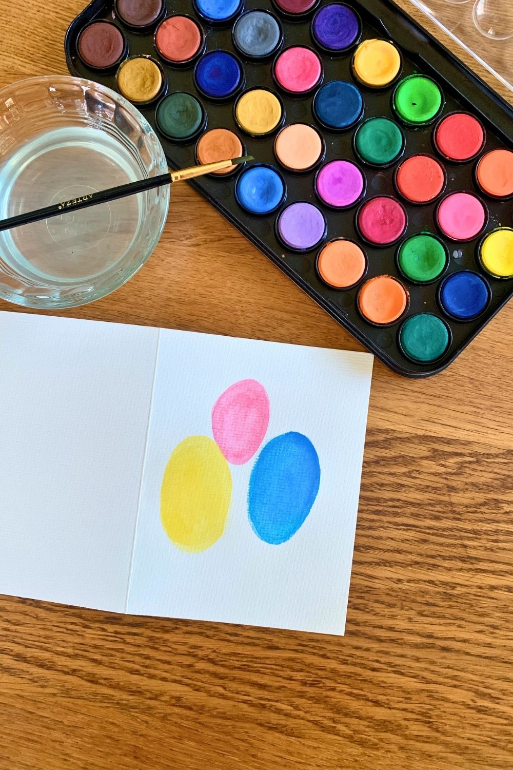 Watercolor ovals in pink, yellow, and blue on paper.