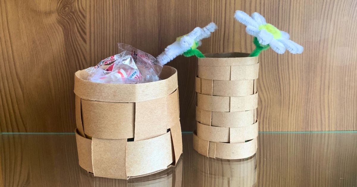 Small paper baskets made from woven kraft paper holding peppermints and faux flowers.