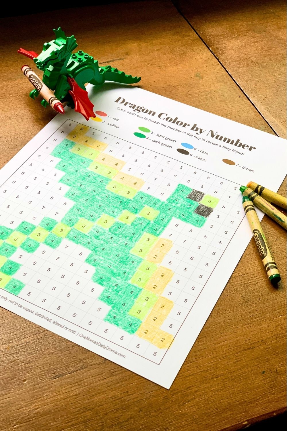 Green and yellow crayons beside a colored gridline worksheet.