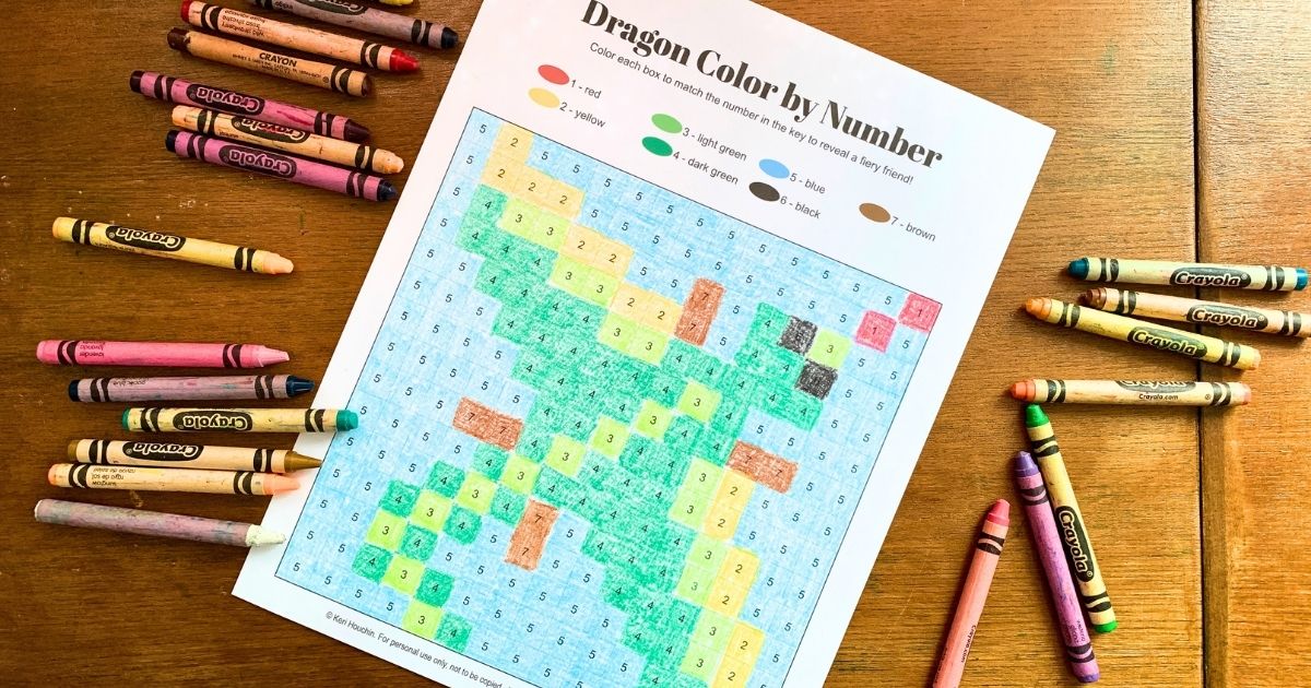 Printable dragon color by number with green, yellow, and blue boxes colored with crayons.