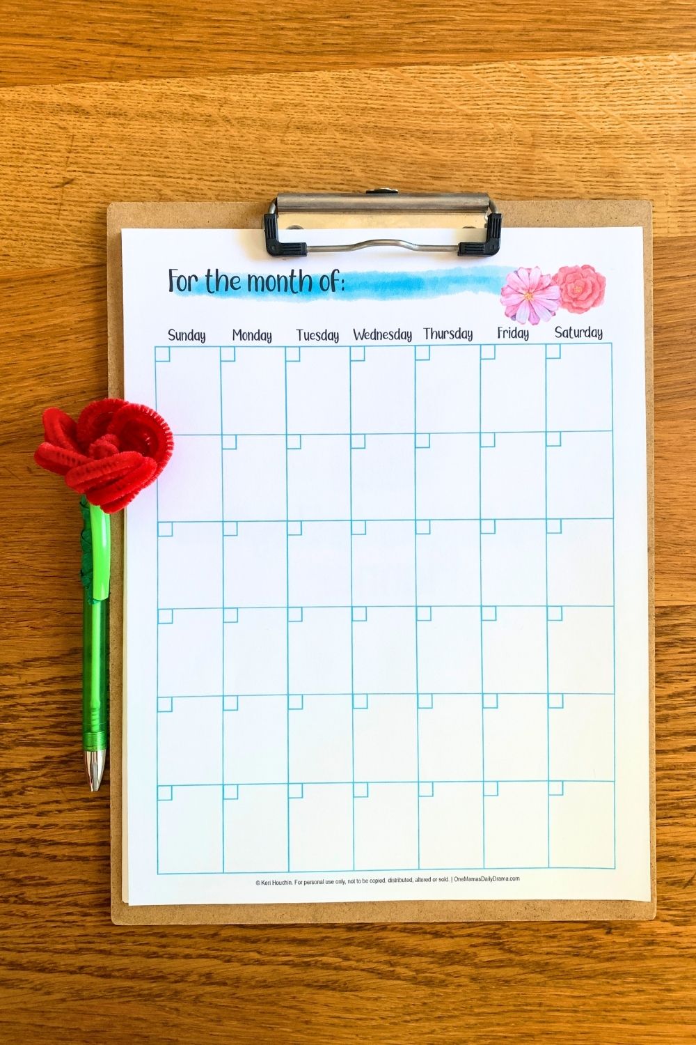 Pipe cleaner rose on the top of a green pen beside a calendar.