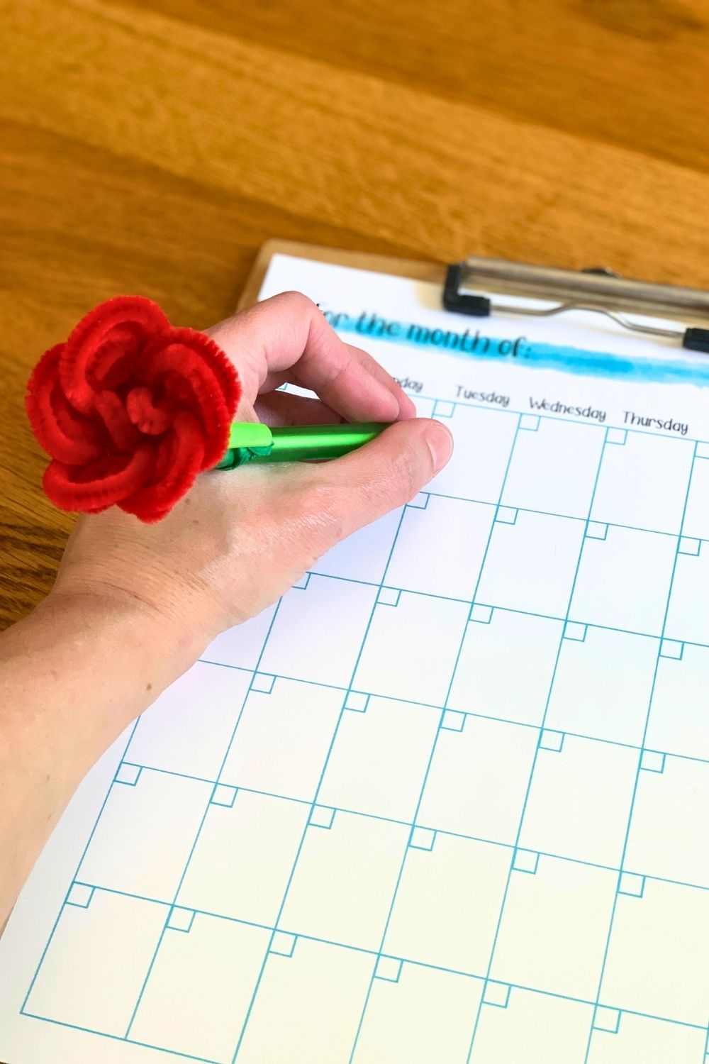Writing with a pen that has a pipe cleaner rose on the end.