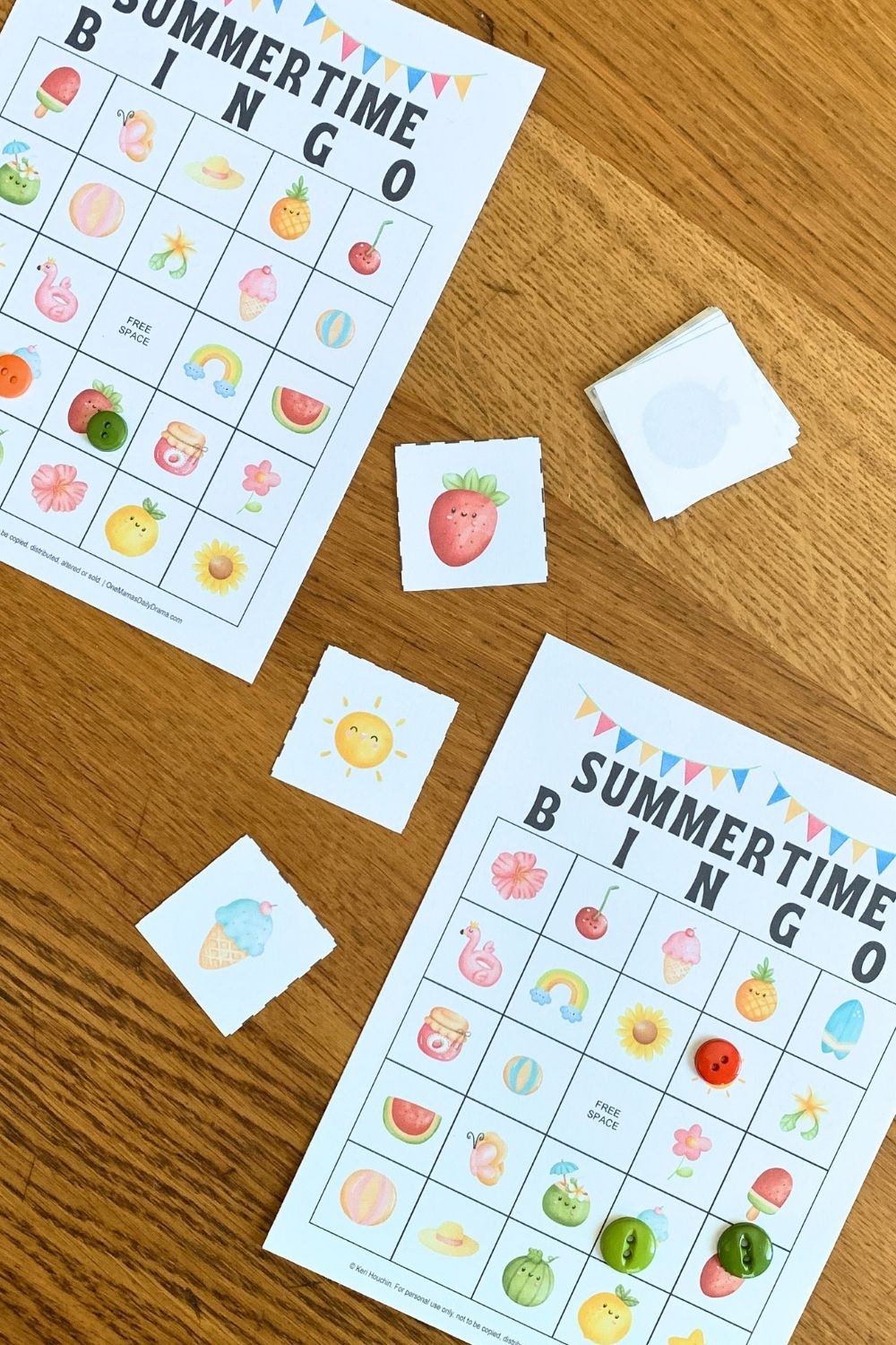 Printed summer bingo cards with buttons covering some squares beside draw cards featuring a strawberry, sun, and ice cream cone.