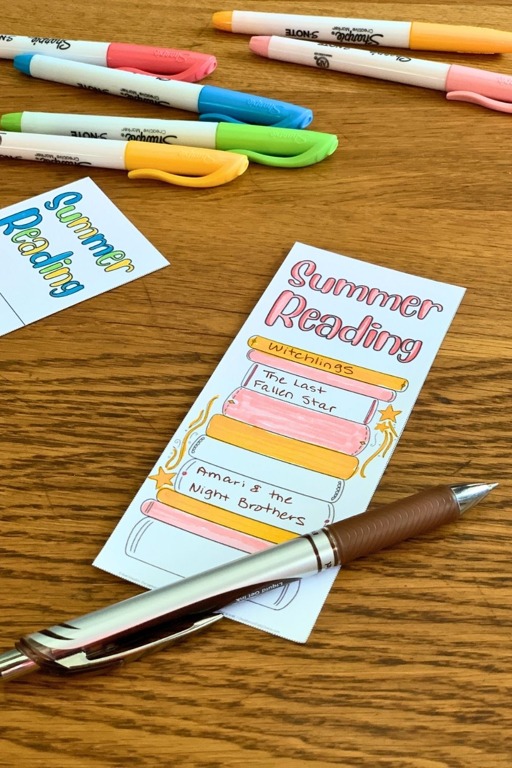 Paper bookmark with book titles written on book spine illustrations and colored pink and yellow.