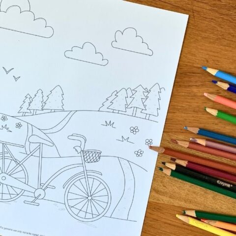 Bicycle coloring page with a cute bike on a trail and flowers, trees, and clouds in the background.
