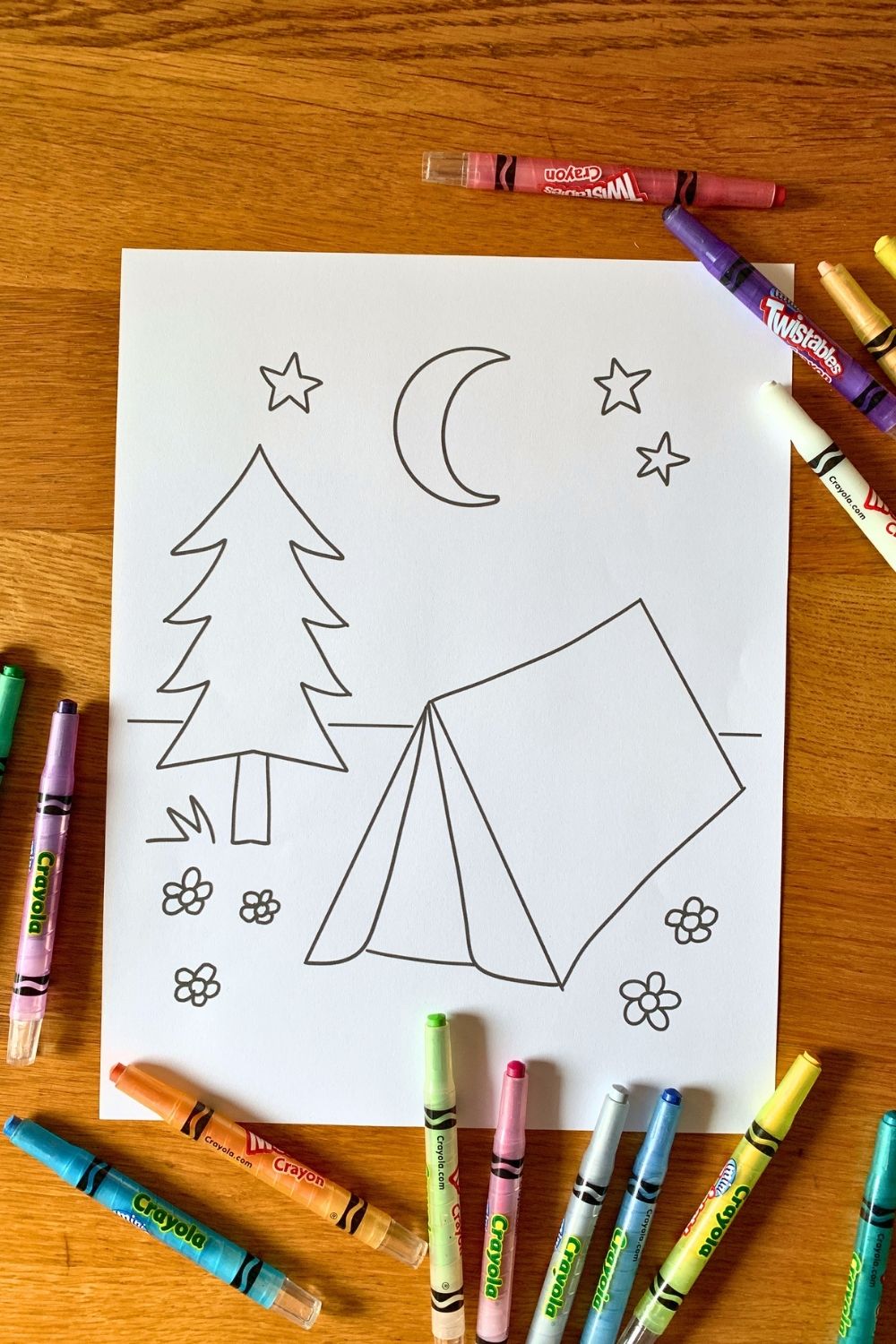 A camping coloring page with a triangle tent beside flowers and a tree with stars and moon above.